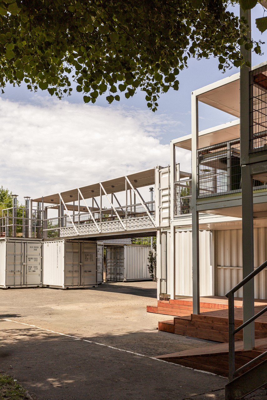 Nowoczesna architektura z kontenerów w zielonym otoczeniu.