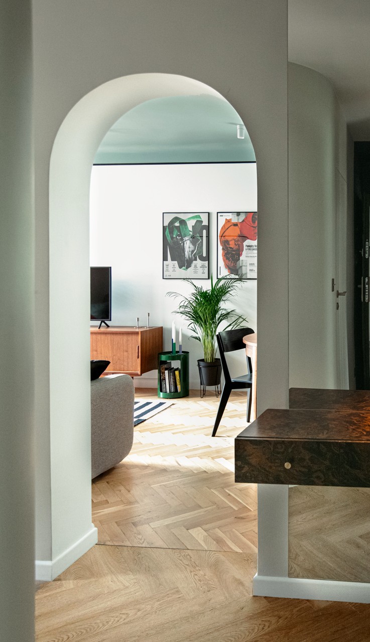Stylowy salon z łukowatym wejściem i designerskimi plakatami.