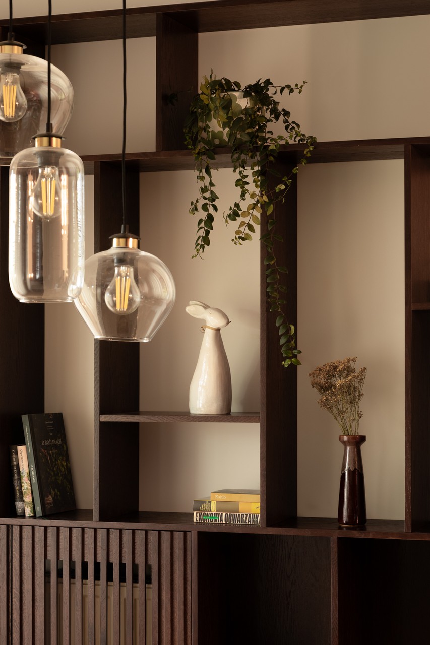 Półka z ceramiką, lampami i książkami w eleganckim wnętrzu.