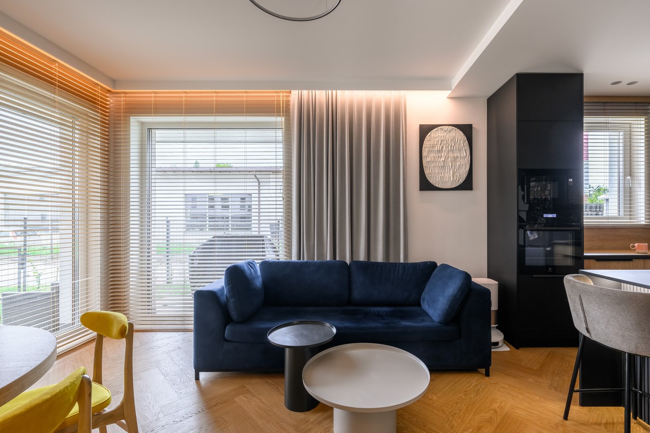 Elegancki salon z granatową sofą i nowoczesnymi dodatkami.
