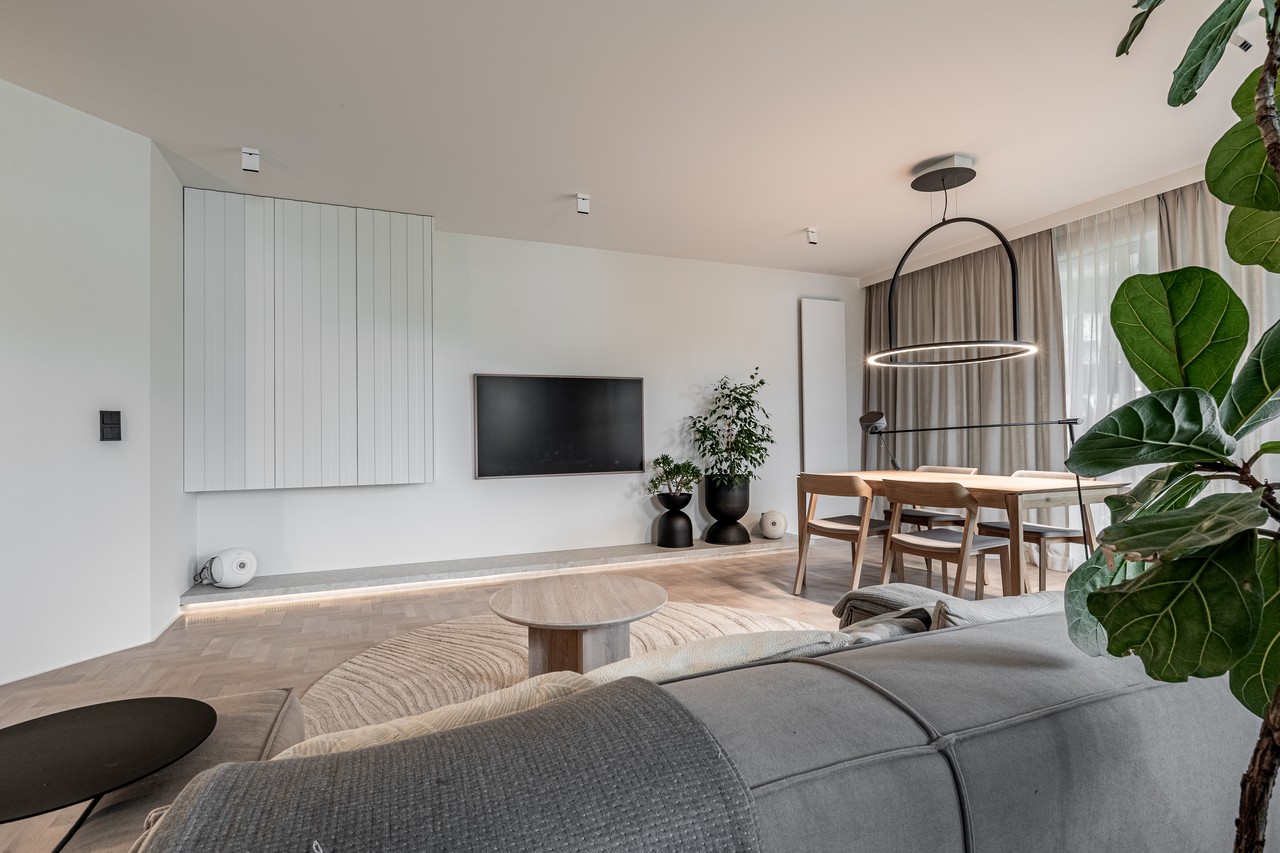 Elegancki salon z designerskim oświetleniem i nowoczesnym stołem.