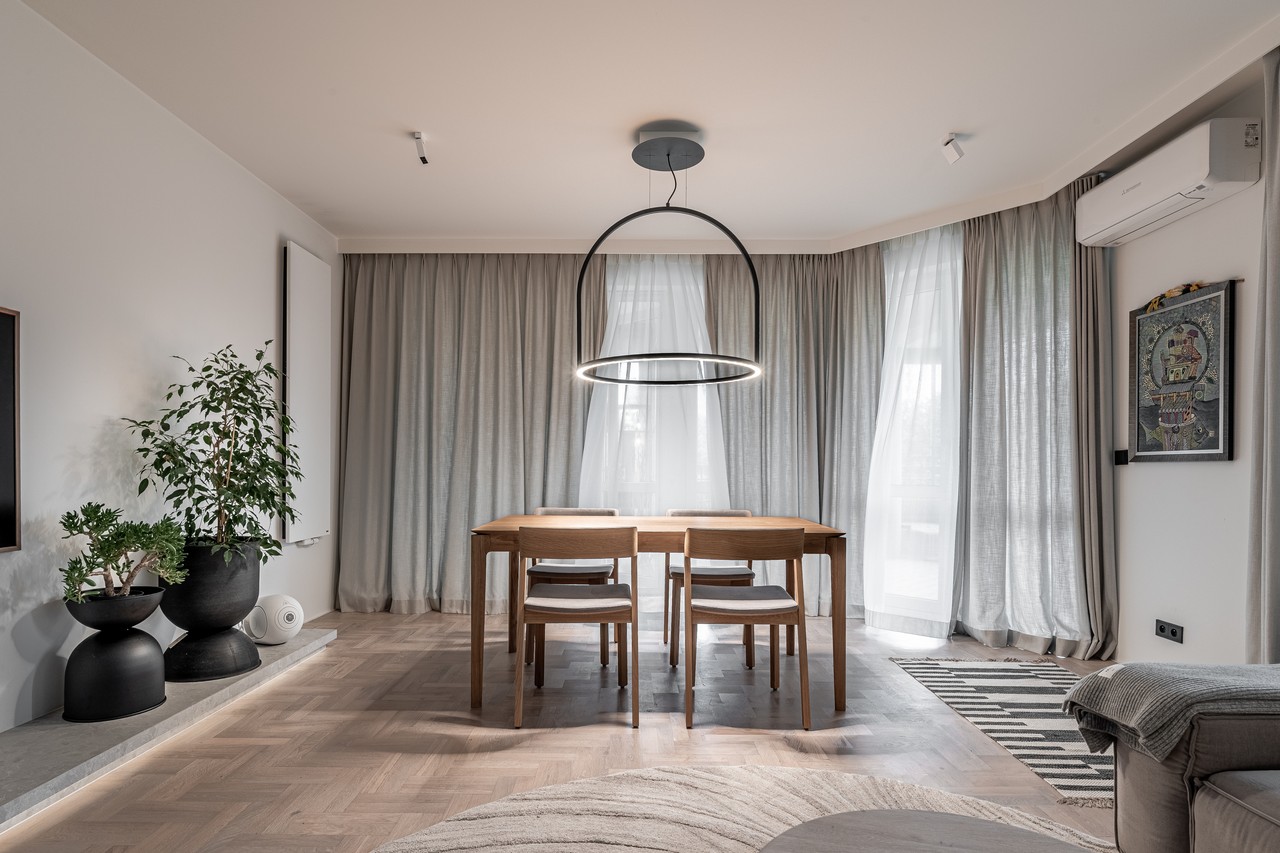 Nowoczesna jadalnia z drewnianym stołem, designerska lampa, rośliny.