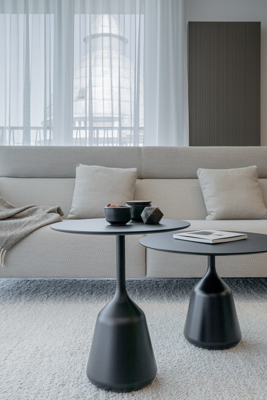Eleganckie wnętrze z sofą i designerskimi stolikami kawowymi.