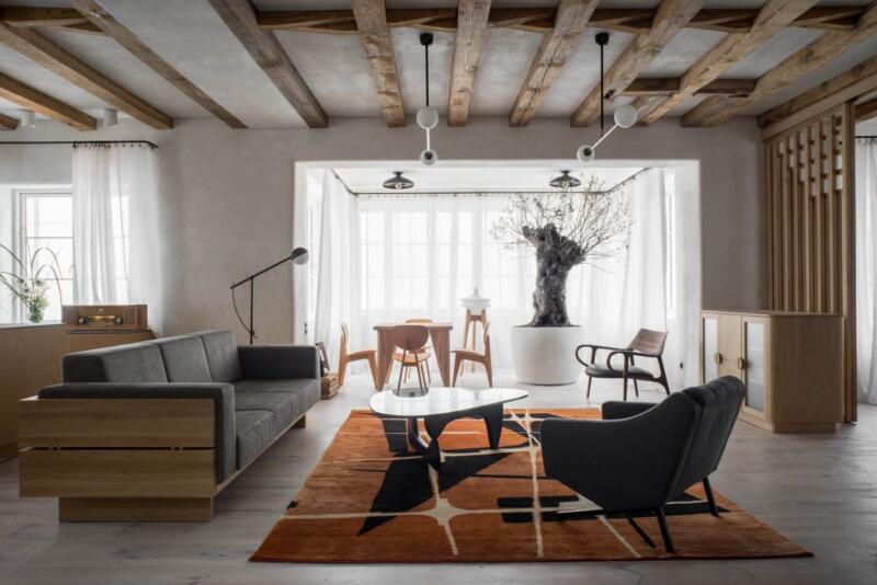 Nowoczesny salon z drewnianym sufitem i designerskim dywanem.