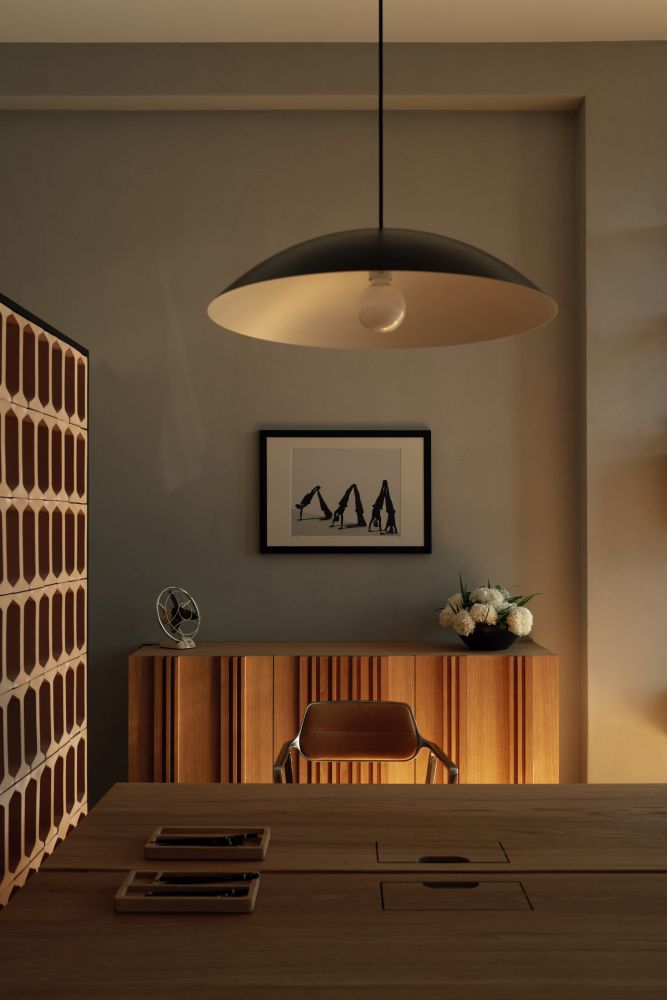 Nowoczesna jadalnia z designerską lampą i drewnianymi meblami.