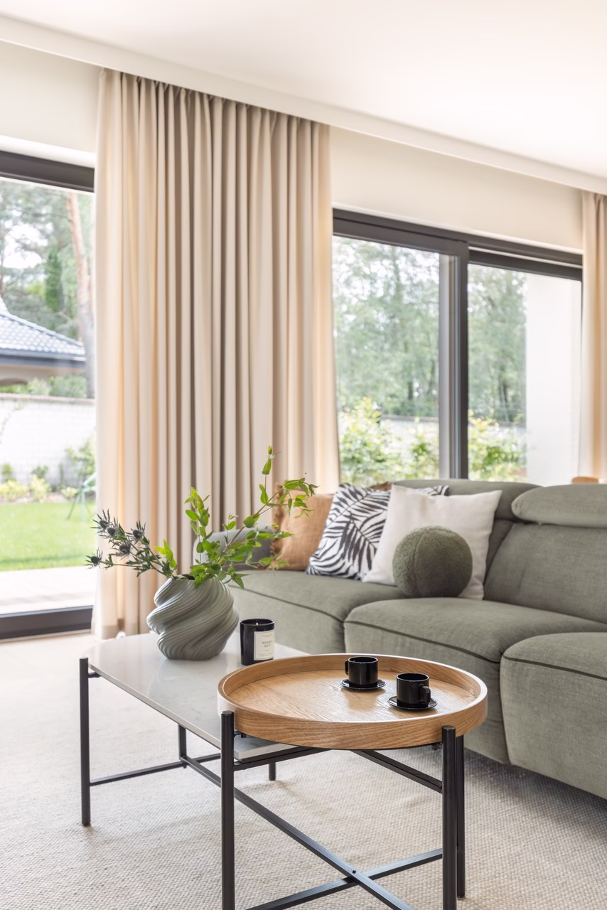Elegancki salon z widokiem na ogród, nowoczesna sofa i stolik.
