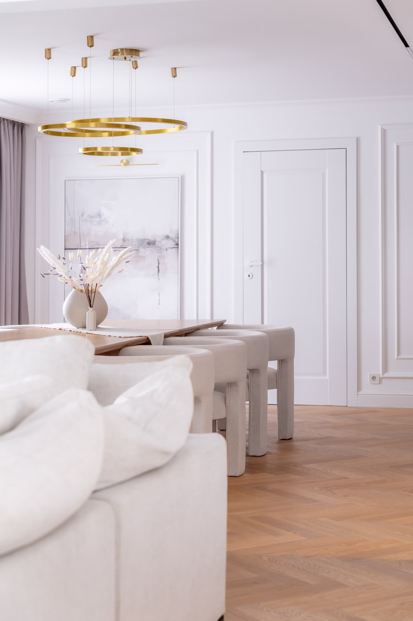 Jasne wnętrze z designerskim złotym żyrandolem i eleganckim stołem.