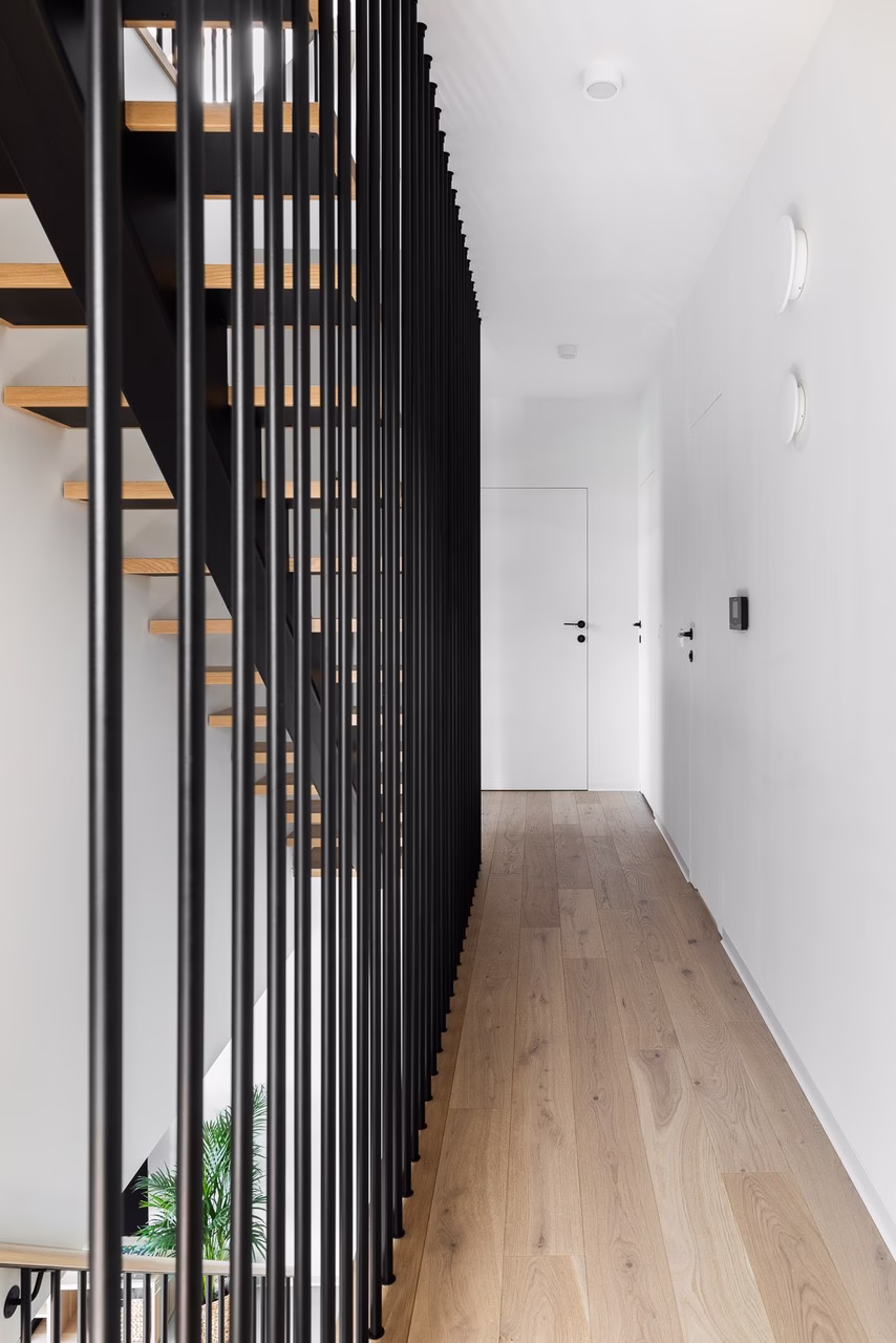 Nowoczesne schody z metalową balustradą i drewnianymi stopniami.