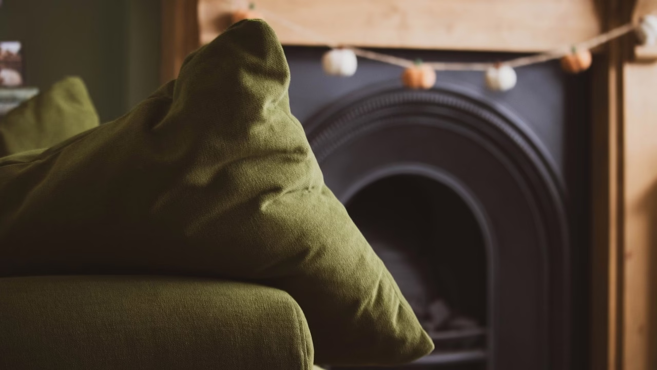 Zielona sofa z eleganckim kominkiem w tle, przytulny design.