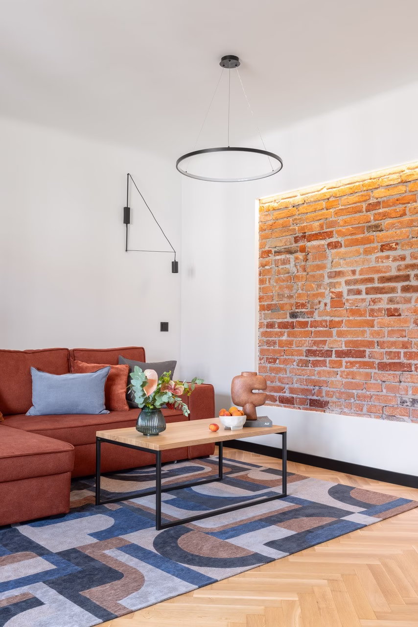 Rustykalny salon z czerwoną kanapą i ceglaną ścianą.