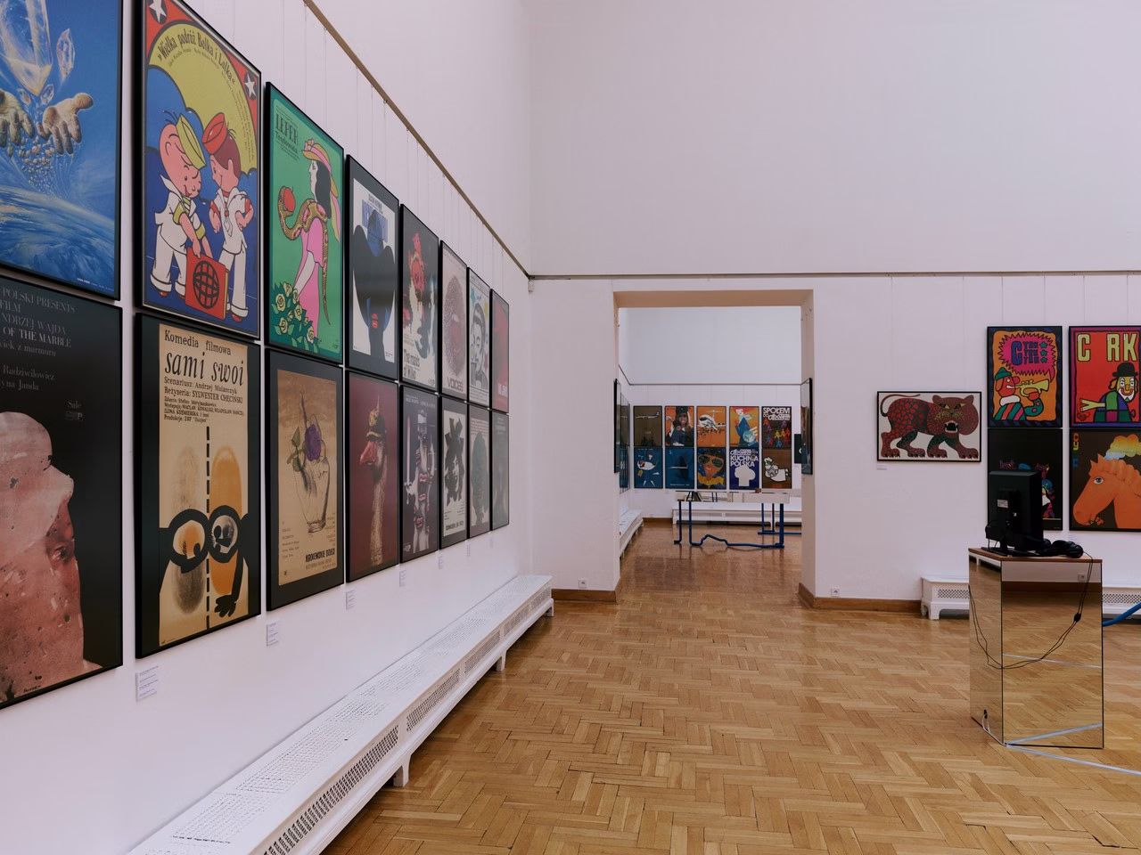 Galeria plakatów w nowoczesnym wnętrzu z jasnym parkietem.