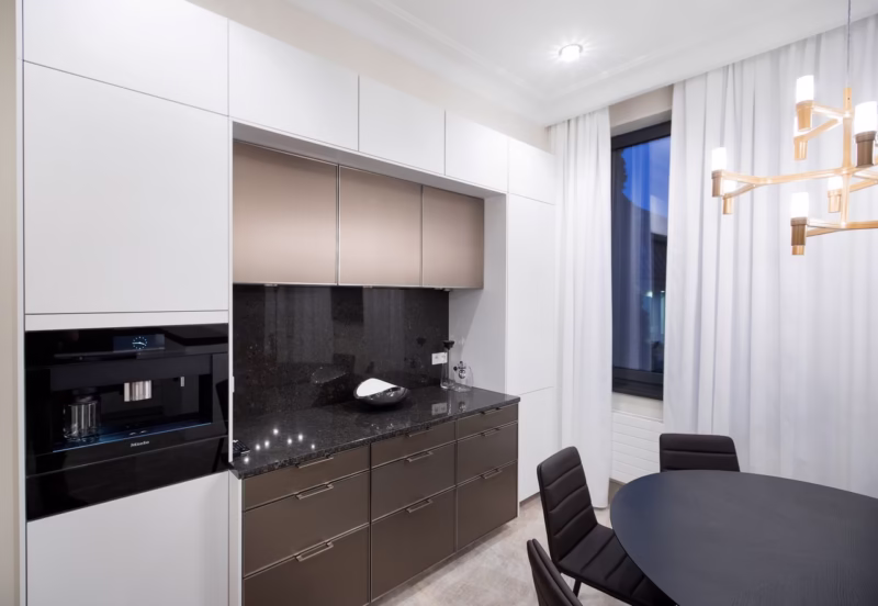 Nowoczesna kuchnia z eleganckim oświetleniem i minimalistycznym stołem.