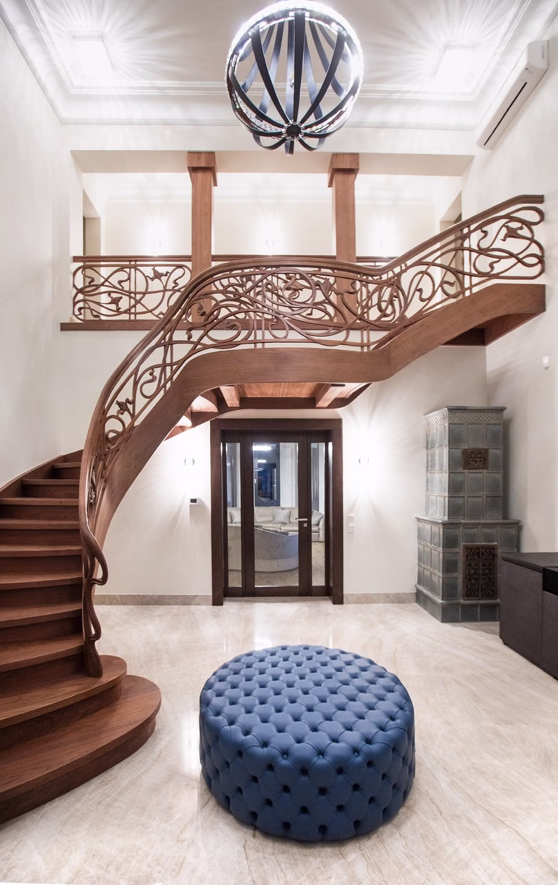 Eleganckie, drewniane schody z misterną balustradą i niebieską pufą.