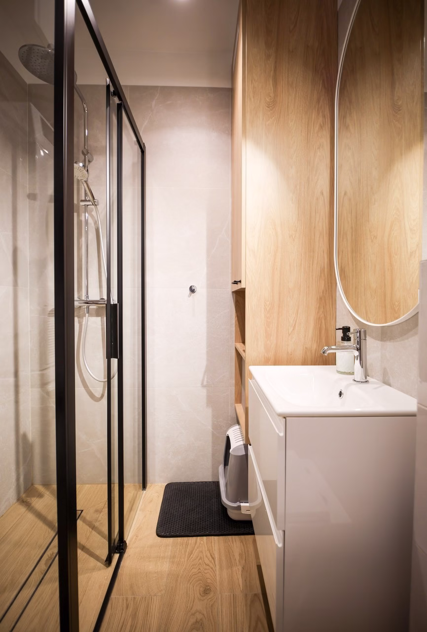 Minimalistyczna łazienka z drewnianymi akcentami, prysznicem ze szklanymi drzwiami