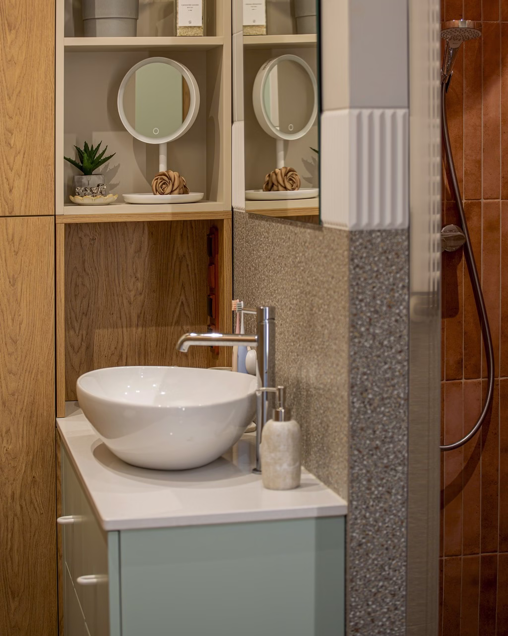 Drewniana łazienka z okrągłym lustrem, białą umywalką i dekoracyjnymi roślinami.