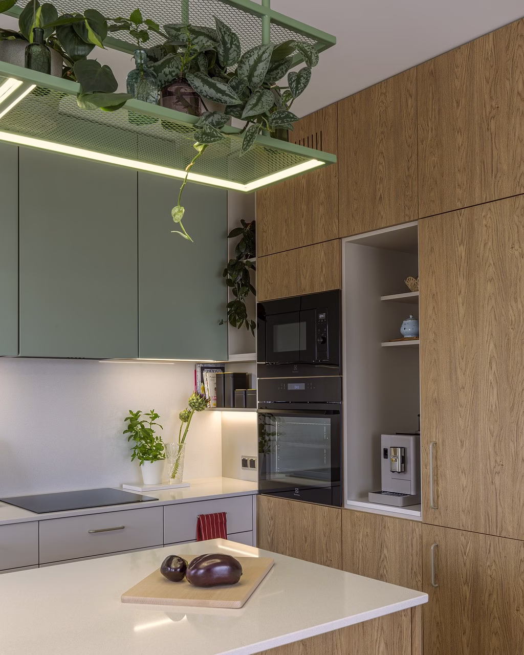 Nowoczesna kuchnia z drewnianymi frontami, zielonymi szafkami i wiszącymi roślinami.