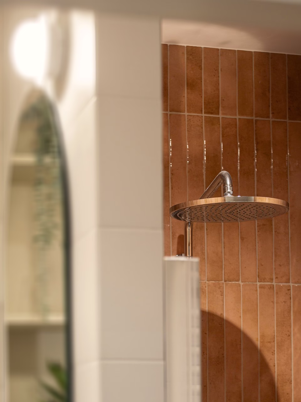 Nowoczesna łazienka z różowymi kafelkami i dużą, okrągłą deszczownicą.