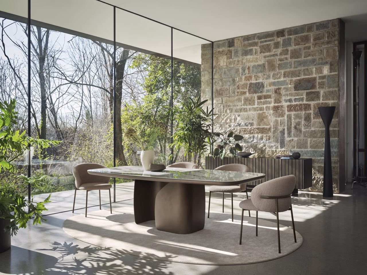Nowoczesna jadalnia z kamienną ścianą, przeszkloną fasadą i roślinami.