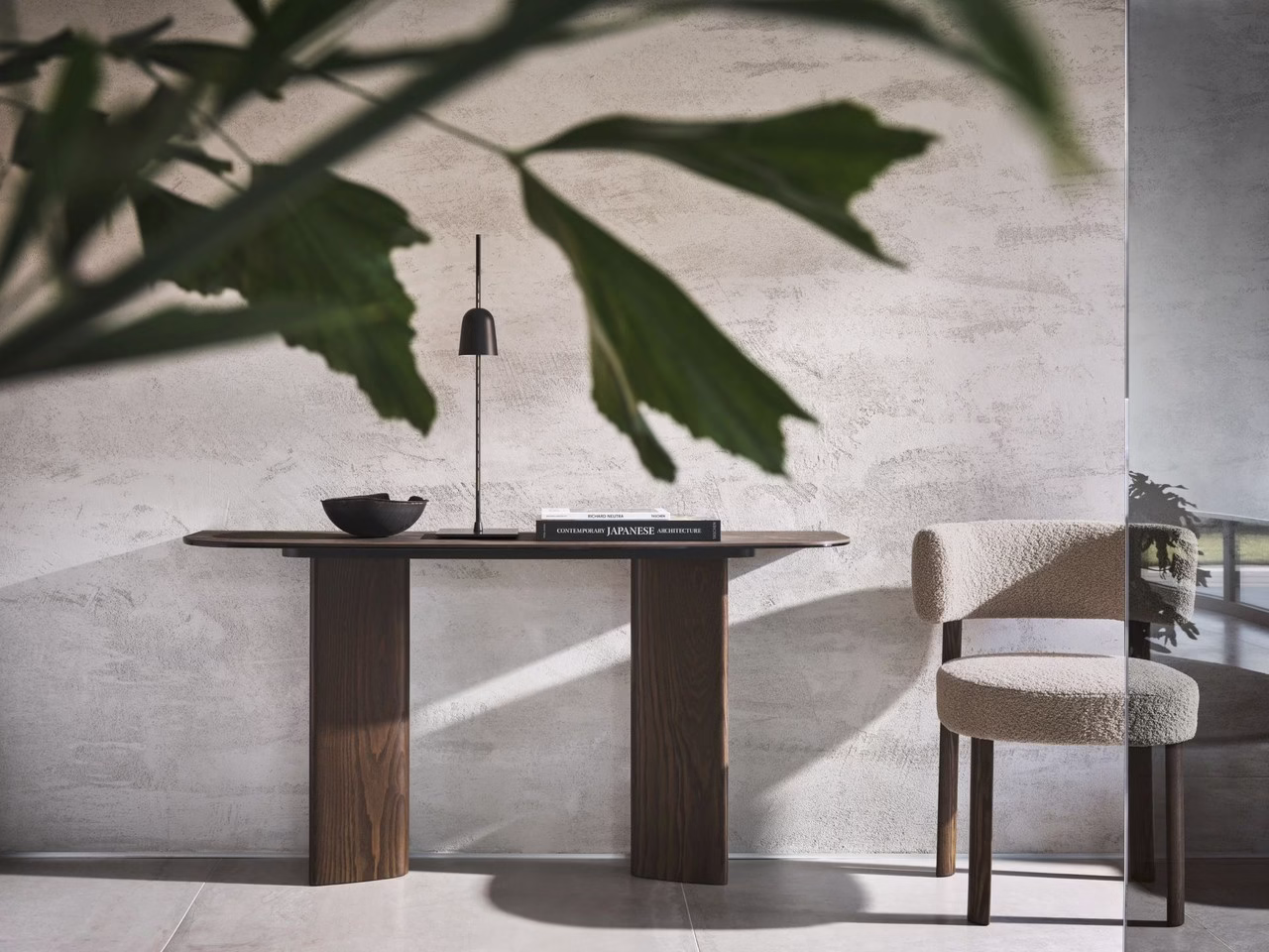 Minimalistyczne wnętrze z drewnianym stołem, kremowym krzesłem i rośliną.