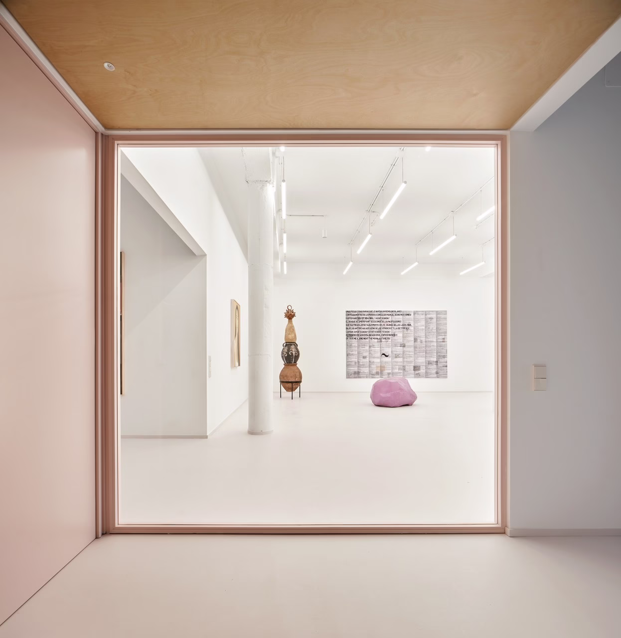 Minimalistyczna galeria sztuki, jasne ściany, nowoczesne rzeźby, białe oświetlenie.
