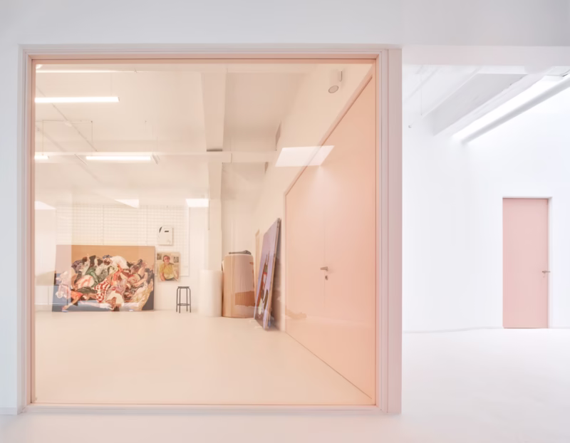 Minimalistyczne wnętrze z pastelowymi drzwiami i obrazami na podłodze.