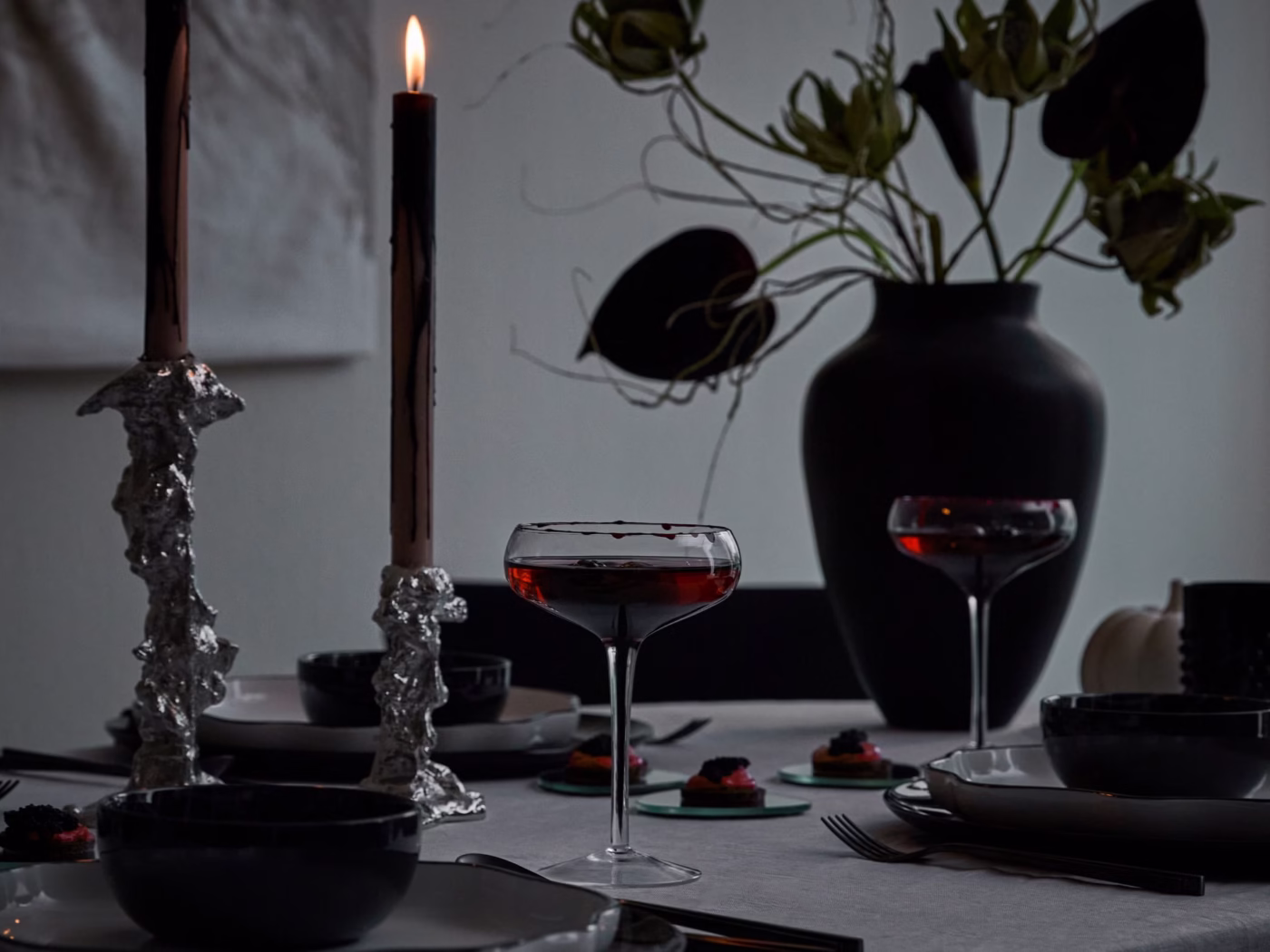 Elegancka dekoracja stołu z ciemnym szkłem i świecami, nastrojowe oświetlenie.