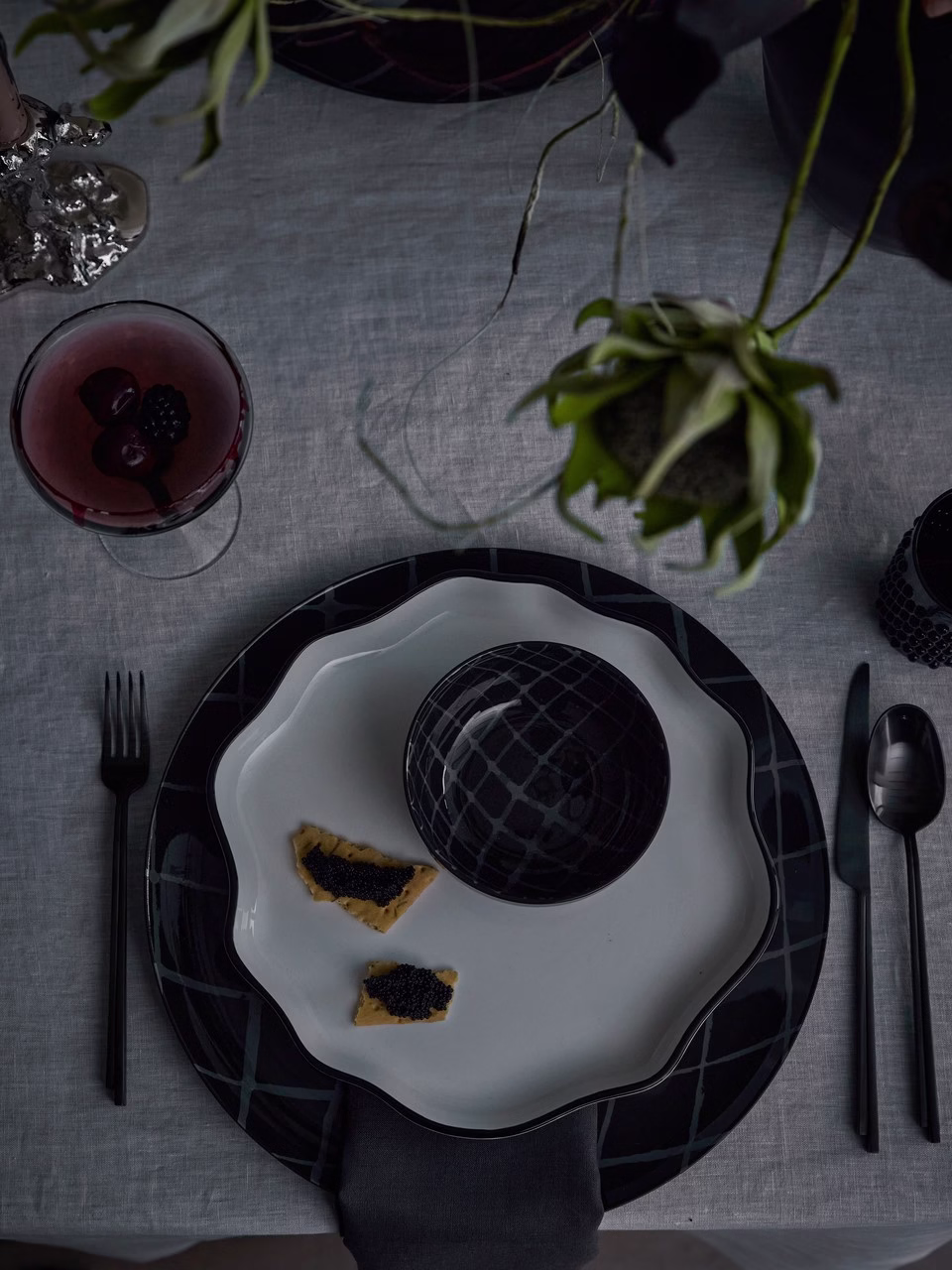 Elegancka zastawa stołowa z czarną porcelaną, krakersami i owocowym drinkiem.