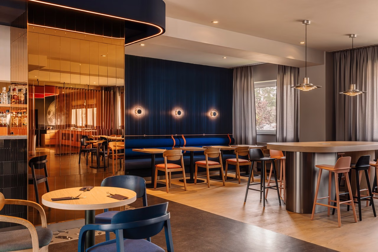 Nowoczesne wnętrze restauracji z drewnianymi krzesłami, niebieskimi ścianami i lustrami.