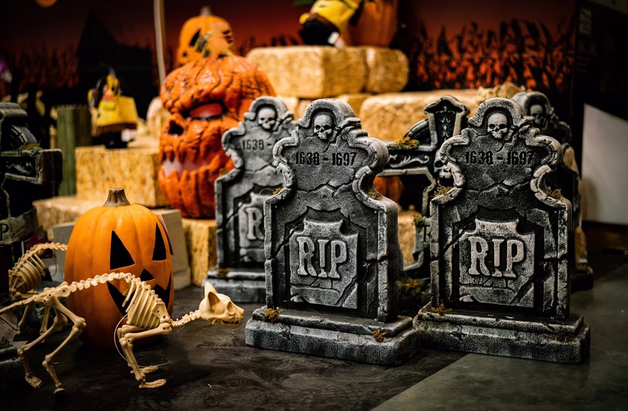Dyniowa dekoracja na Halloween z grobowcami i szkieletem kota.