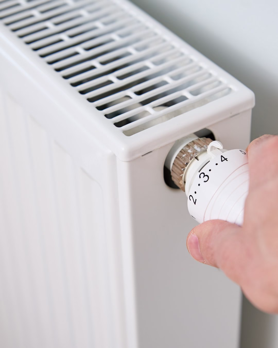 Biały grzejnik z regulatorem temperatury, jasne wnętrze mieszkania.