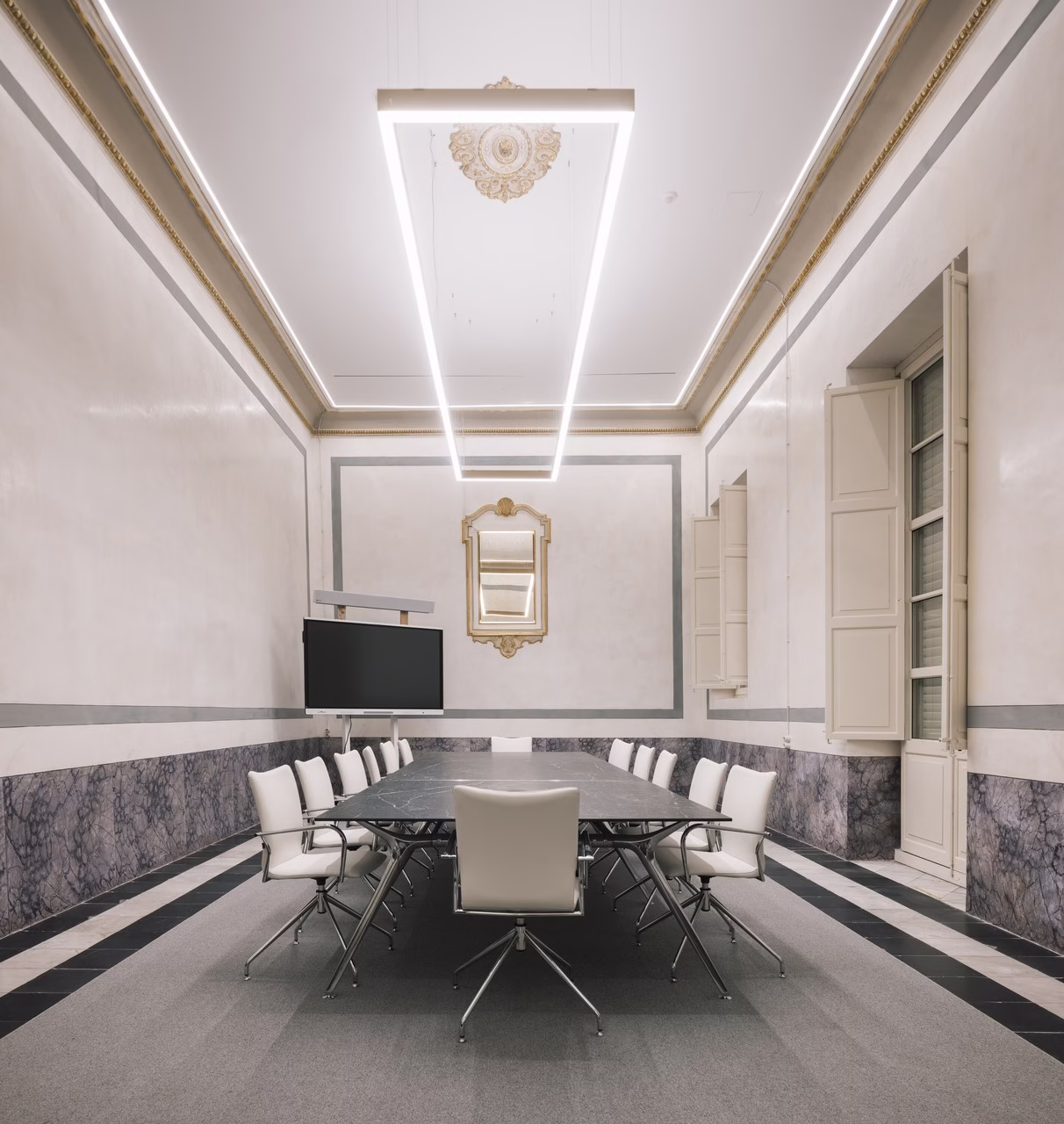 Elegancka sala konferencyjna z białymi krzesłami, stropem LED i lustrem.