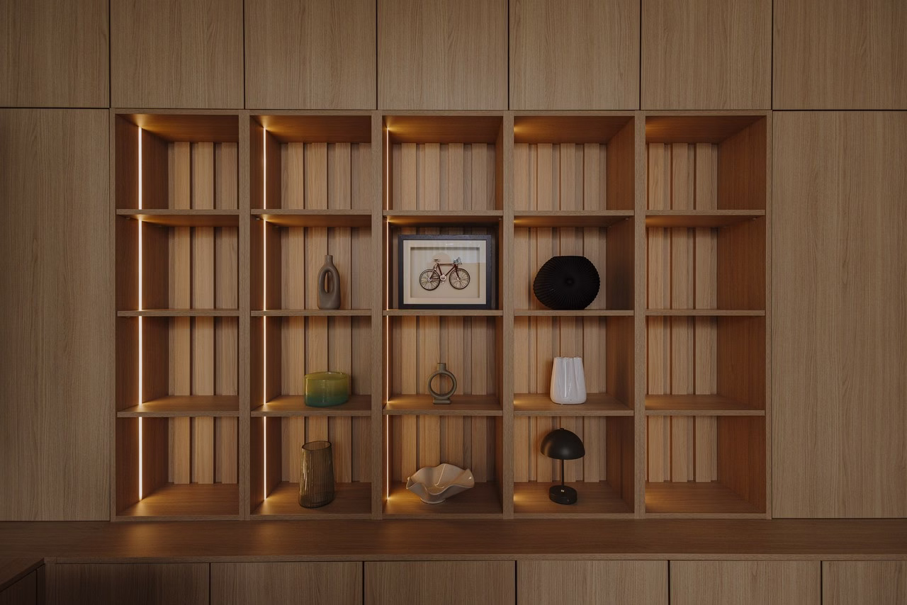 Drewniana biblioteczka z oświetleniem, wazonami i obrazkiem roweru, nowoczesny design.