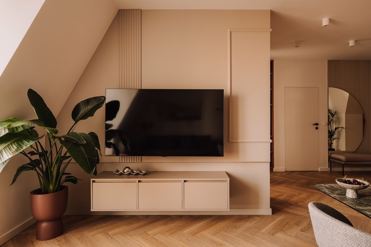 Nowoczesny salon z beżowymi ścianami, drewnianą podłogą i dużym telewizorem.