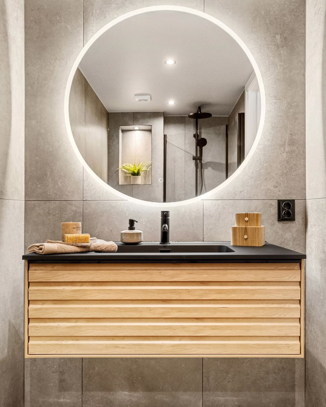 Nowoczesna łazienka z podświetlanym lustrem, drewniana szafka, kamienna umywalka.