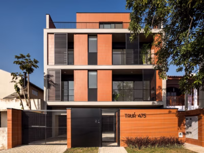 Nowoczesny budynek z pomarańczowej cegły i metalowymi panelami.