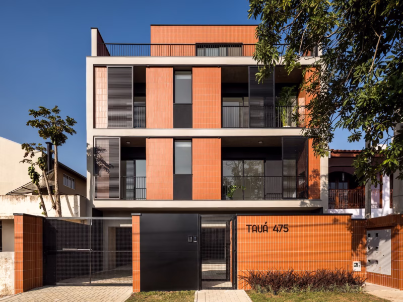 Nowoczesny budynek z pomarańczowej cegły i metalowymi panelami.