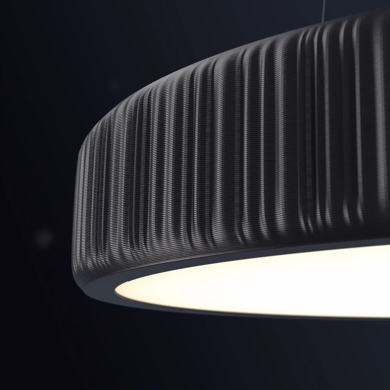 Nowoczesna, czarna lampa wisząca z teksturą na tle ciemnej ściany.