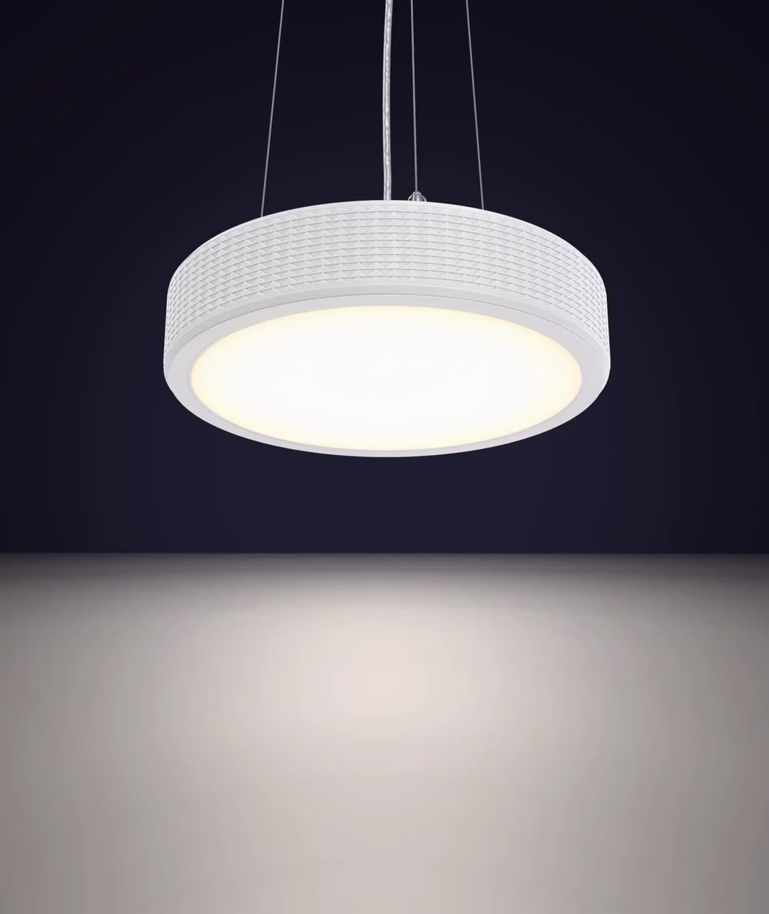 Nowoczesna, biała lampa wisząca z wzorzystym kloszem na ciemnym tle.