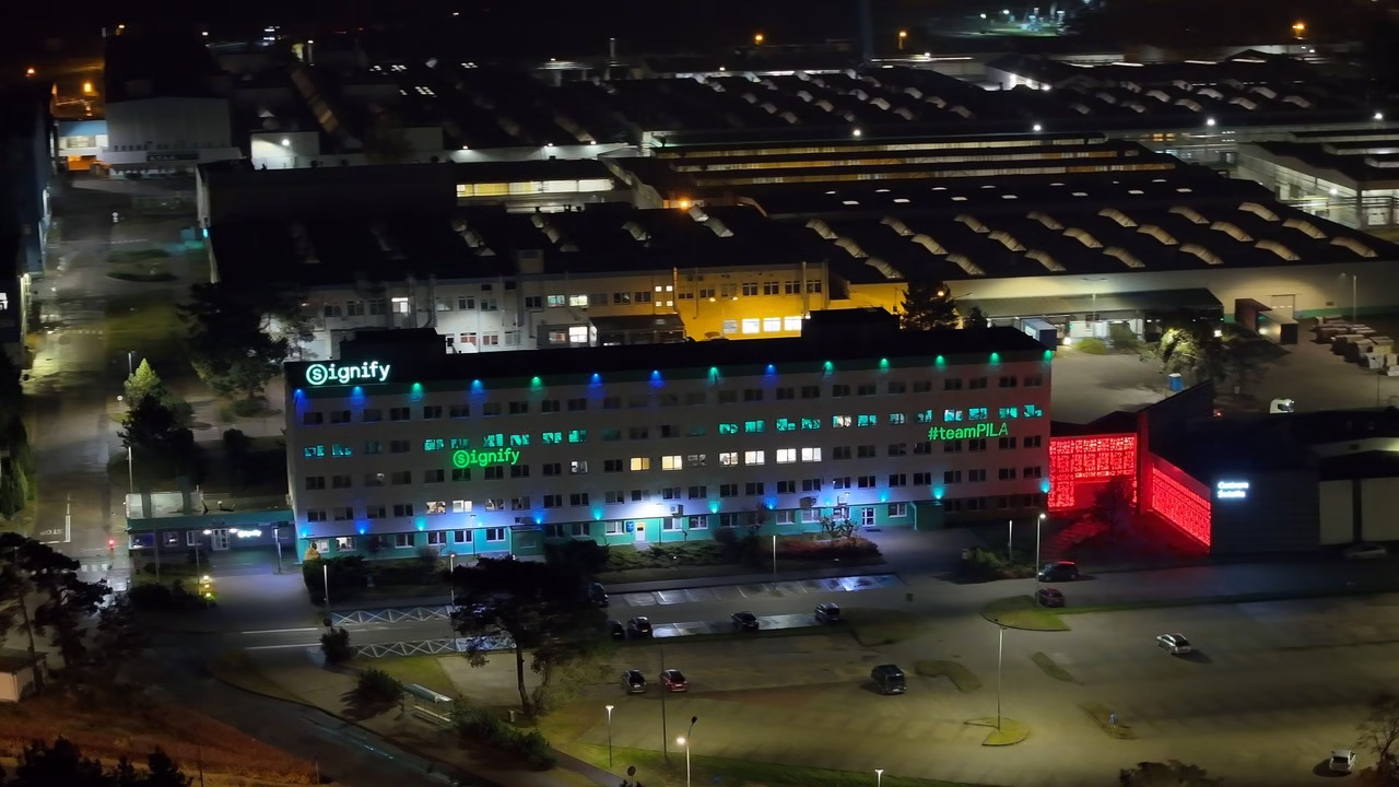 Nocny widok fabryki Signify z podświetlonymi logami i kolorowymi lampami.
