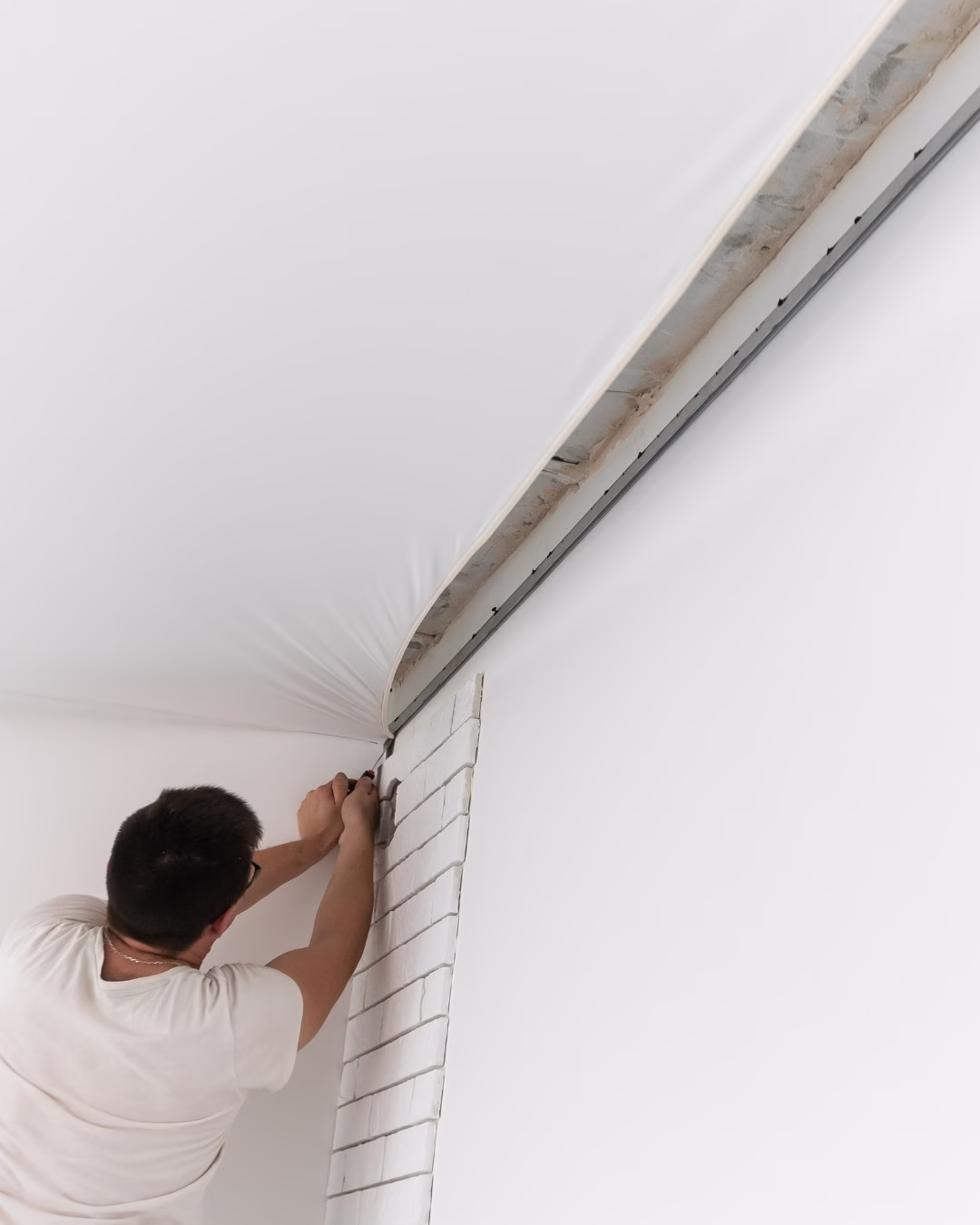 Instalacja białego sufitu napinanego w minimalistycznym jasnym wnętrzu.