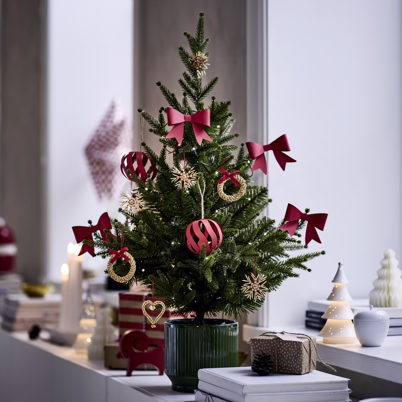 Świąteczne drzewko dekoracyjne z czerwonymi kokardami i złotymi ozdobami.