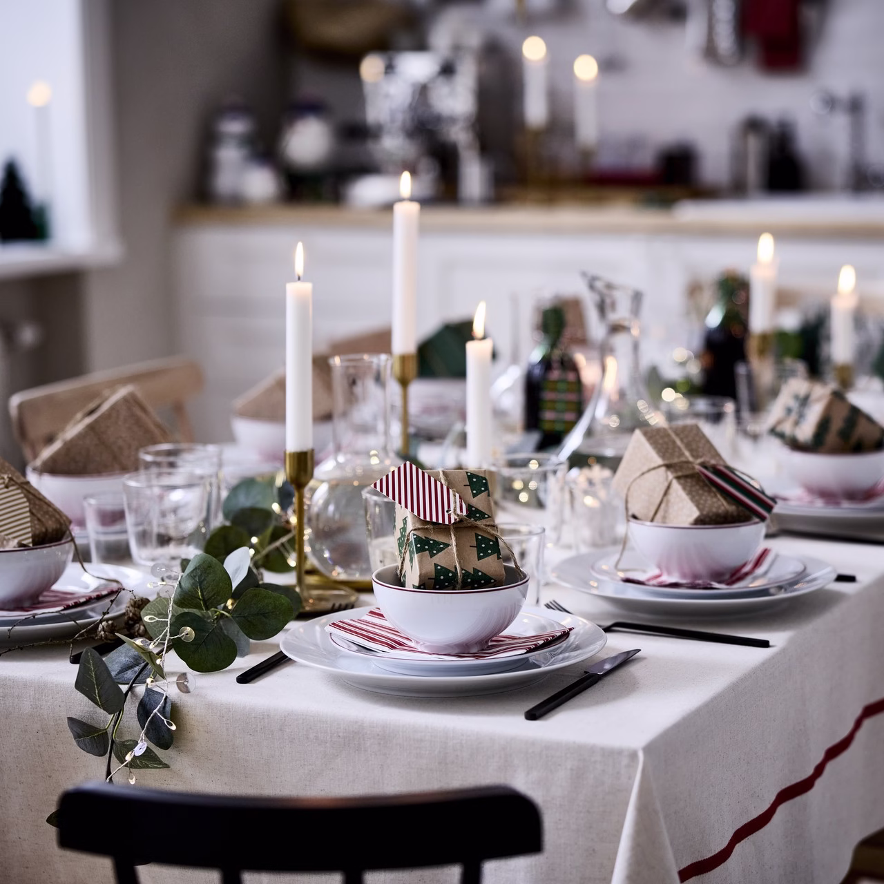 Elegancka świąteczna dekoracja stołu z jasnymi świecami i zielonymi gałązkami.
