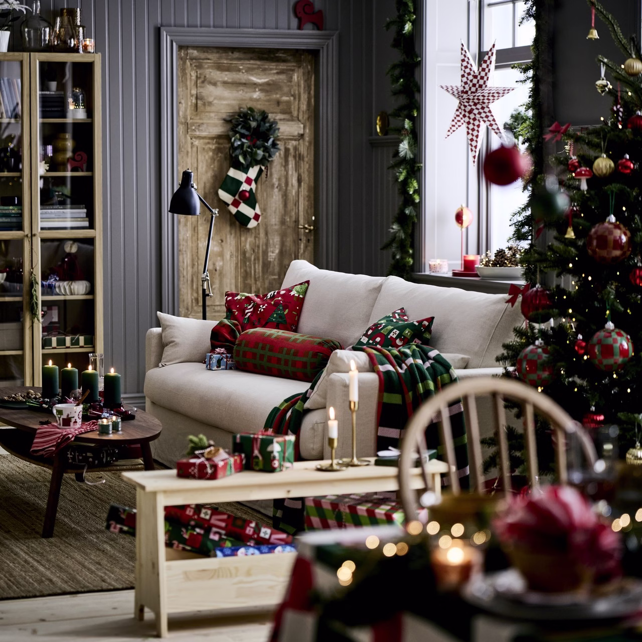 Świąteczny salon z zielono-czerwonymi akcentami, choinką i jasną sofą.