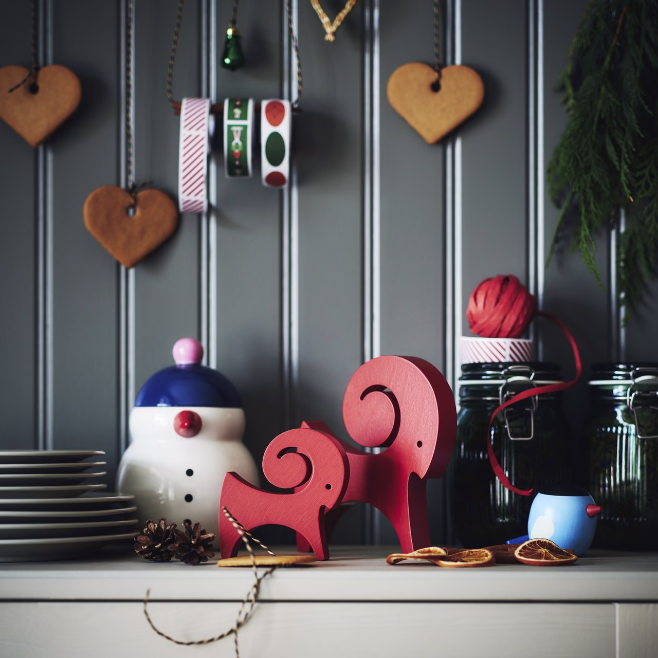 Szare panele, czerwone figurki, ceramiczny bałwanek, świąteczne detale, rustykalny styl.