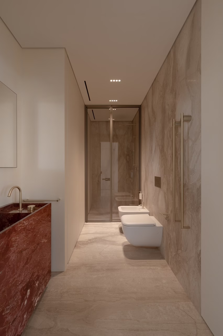 Minimalistyczna łazienka z czerwonym marmurem, elegancką ceramiką i złotymi akcentami.