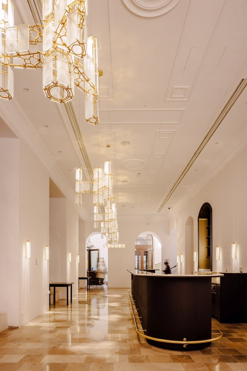 Elegancki hol z marmurową podłogą, złote lampy, klasyczne łuki.