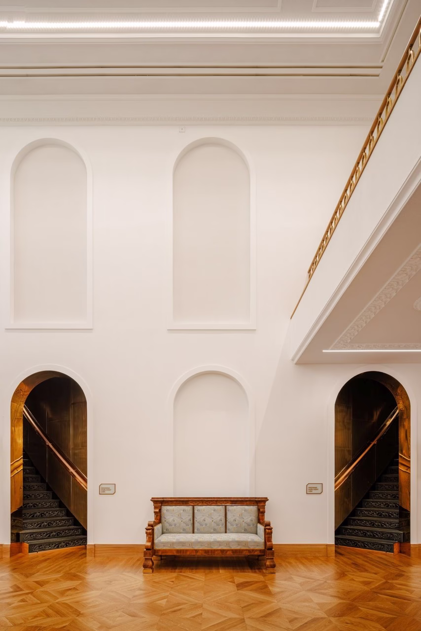 Stylowe wnętrze z drewnianą podłogą, klasyczną sofą i schodami w łukach.