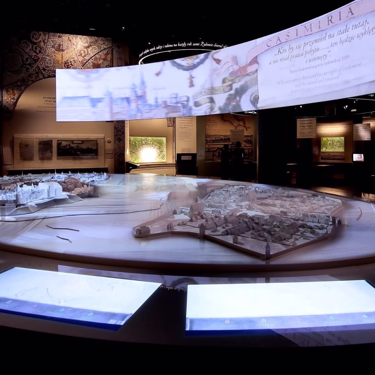 Interaktywne muzeum z makietą miasta, wiszącymi ekranami i mapami.