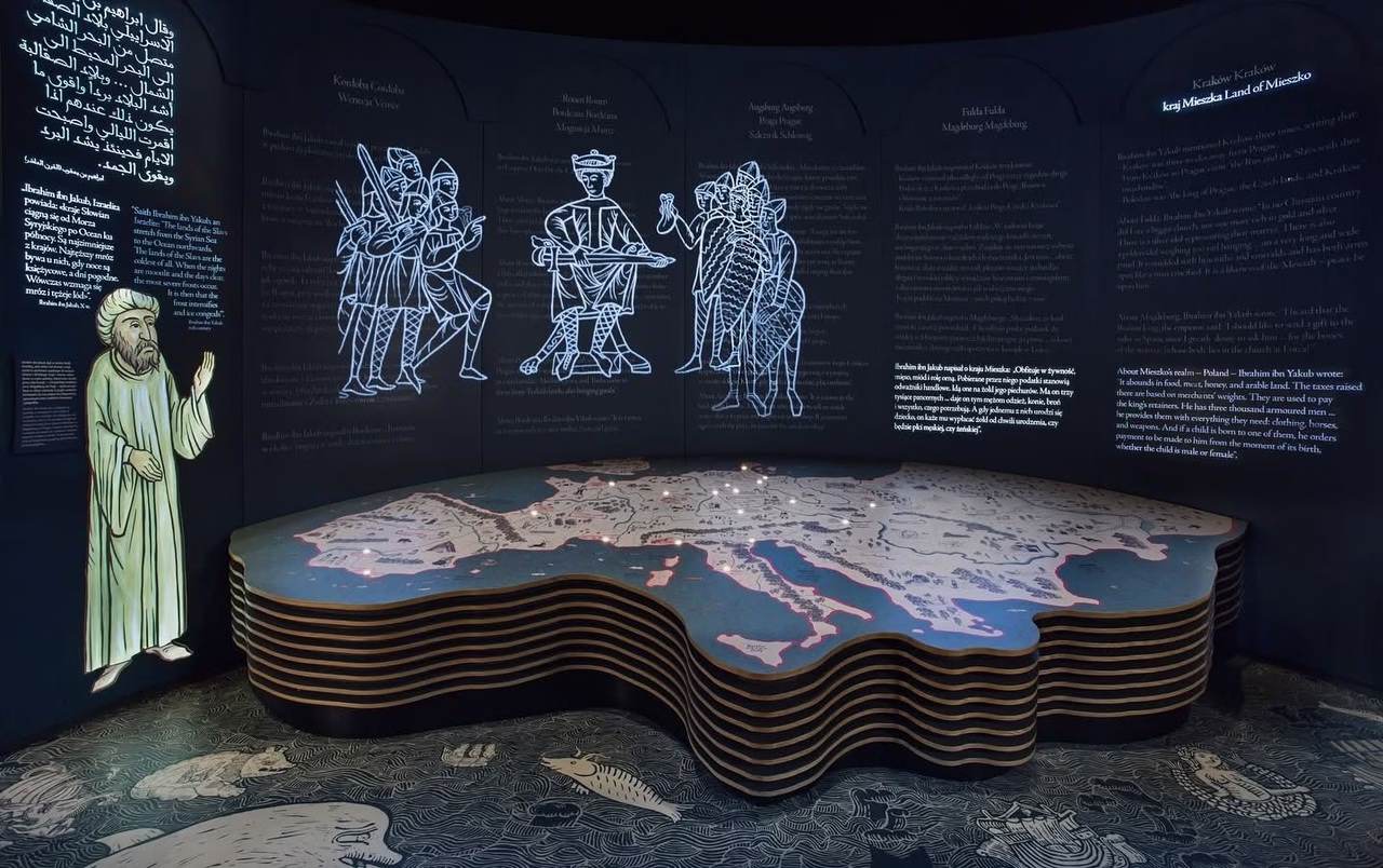 Interaktywna mapa z podświetleniami, stylizowane postacie na ścianie wystawowej.