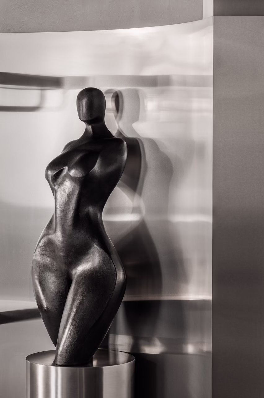 Czarna rzeźba kobieca na tle lustrzanej ściany, nowoczesny design.